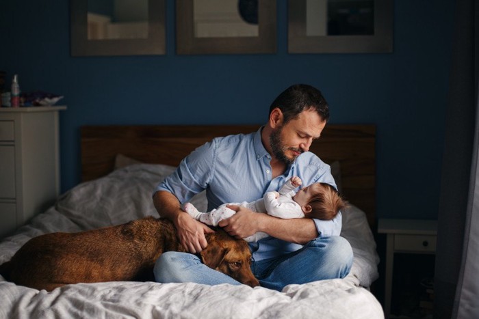 赤ちゃんを抱く父親と寄り添う犬