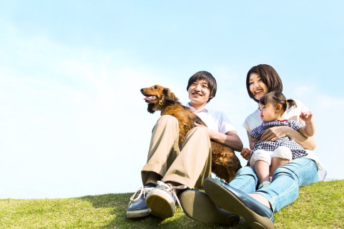 芝生の上に座る家族と犬