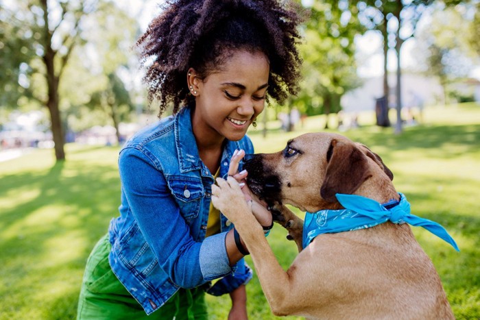 公園で触れ合う女性と青いバンダナの犬
