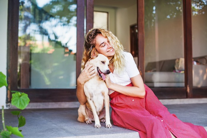犬と寄り添う赤いスカートの金髪女性