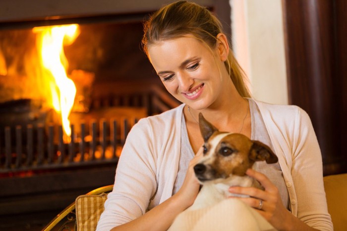 暖炉の前でくつろぐ女性と犬