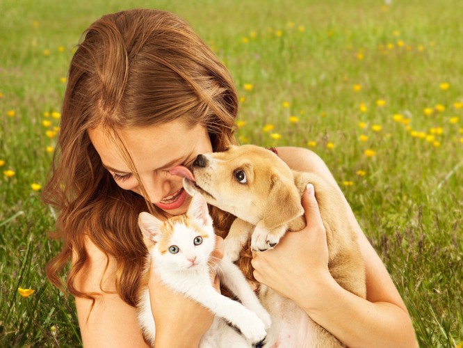 犬と猫を抱きしめる女性