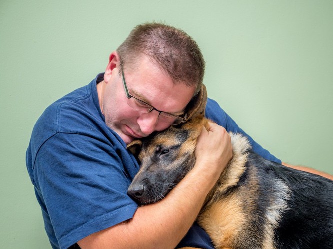 目を閉じて犬を抱きしめる男性