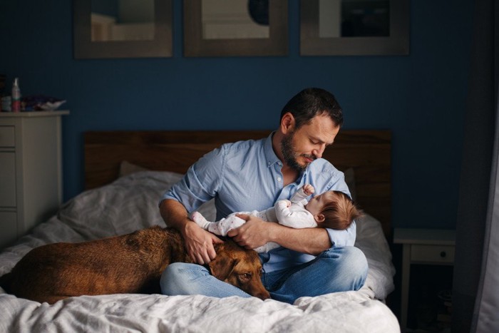 犬と赤ちゃんを抱っこする男性