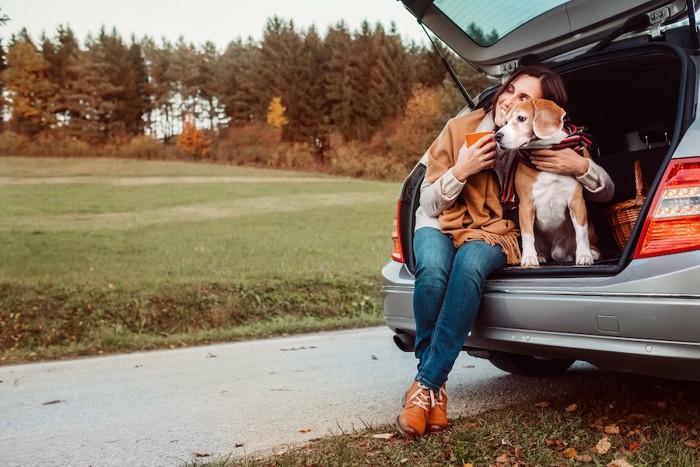 車のトランクに座る女性と犬