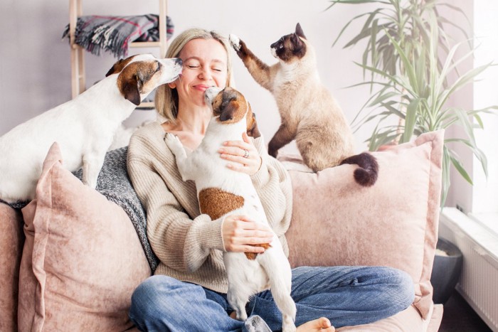 犬と猫に囲まれて幸せそうな女性