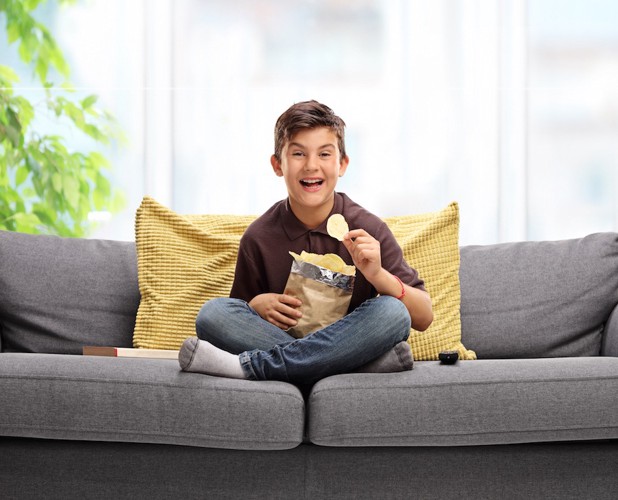 ソファーでポテトチップスを食べる少年